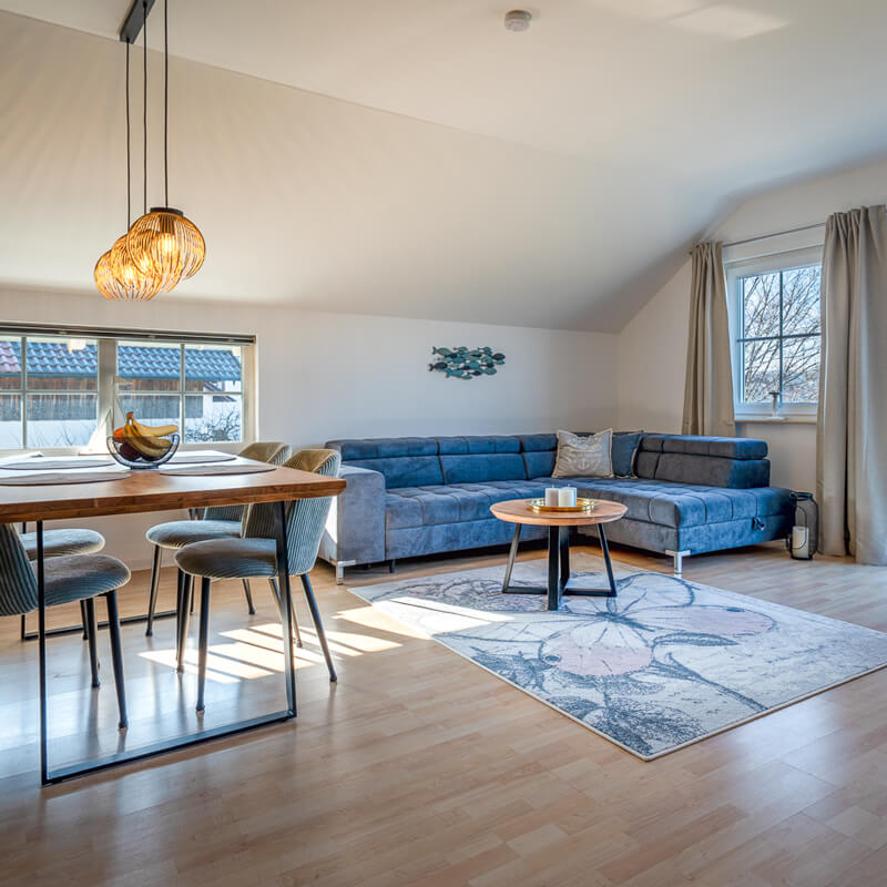 Wohnzimmer mit großer Couch und Essbereich in der Ferienwohnung Lüftenblick am Starnberger See
